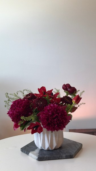 Burgundy dahlias, red lilies, and dark tulips in a white ribbed vase