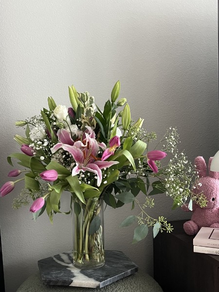 Pink stargazer lilies, tulips, and baby's breath in a glass vase